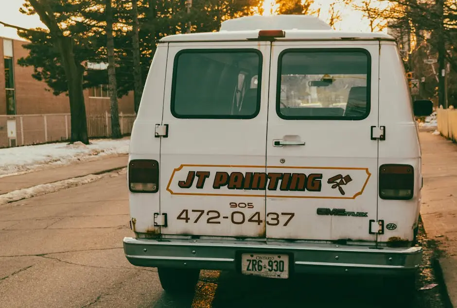Rear view of a vintage painting service van parked on a snowy street during winter sunset.