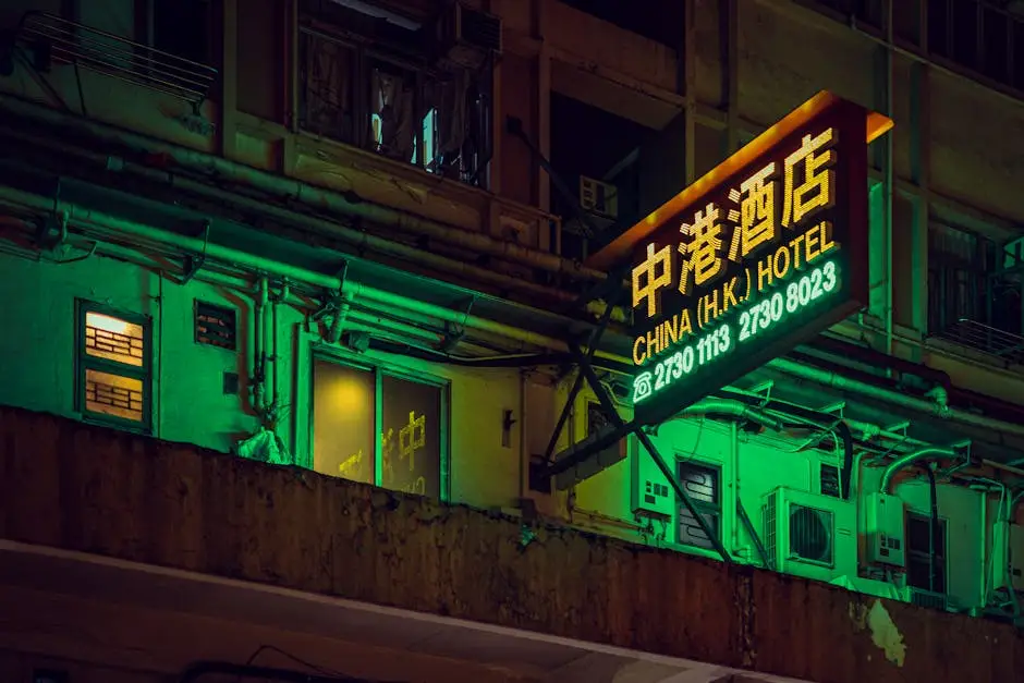 A neon-lit hotel sign illuminates the bustling streets of Hong Kong, capturing the city's vibrant nightlife.